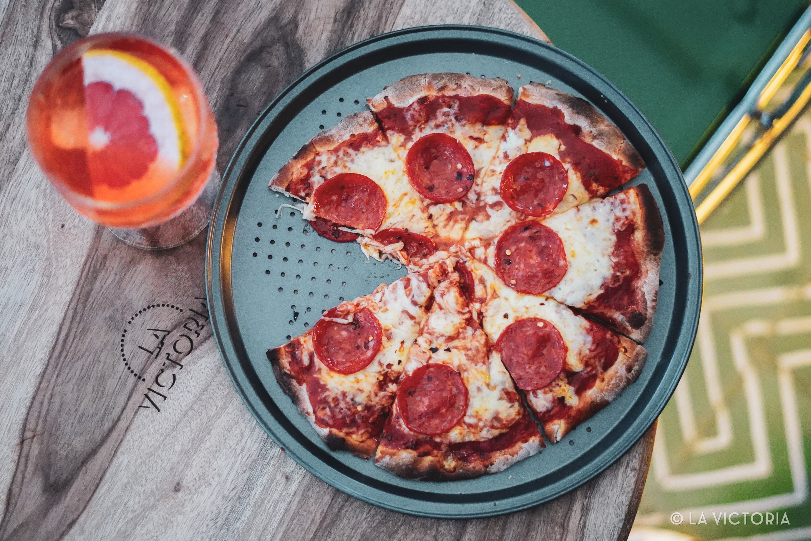 Pizza recién horneada junto a un cóctel